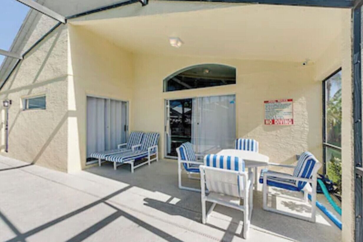A covered outdoor seating area with lounge chairs and a table, a covered entrance, and a sign indicating a private area.