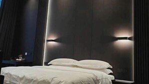 Ein modernes Hotelzimmer mit einem großen Bett, dunklen Holzpaneelen und Wandleuchten.