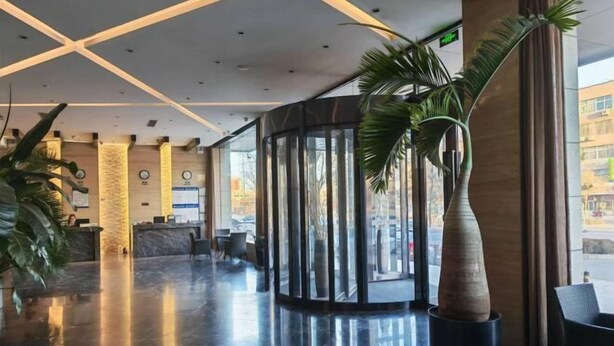 Eine moderne Lobby mit glänzendem Marmorboden, einer Rezeption und einer großen Glasscheibe.