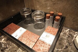 Ein Tablett mit verschiedenen Gegenständen, darunter Flaschen und Musterboxen, vermutlich Teil der Ausstattung eines Hotels.