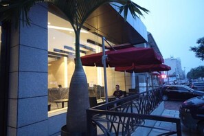Un edificio moderno con fachada de vidrio, zona de estar al aire libre y una palmera.