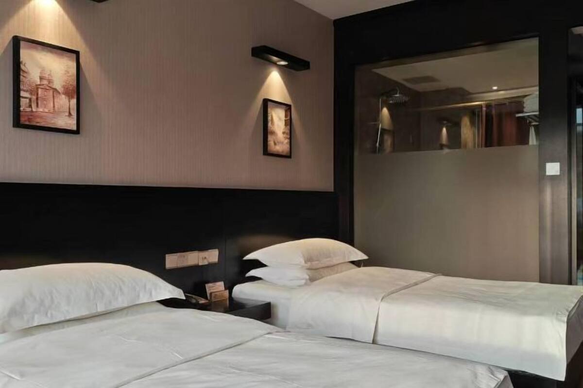 Habitación de hotel con dos camas, cabecero, obra de arte en la pared y un espejo.
