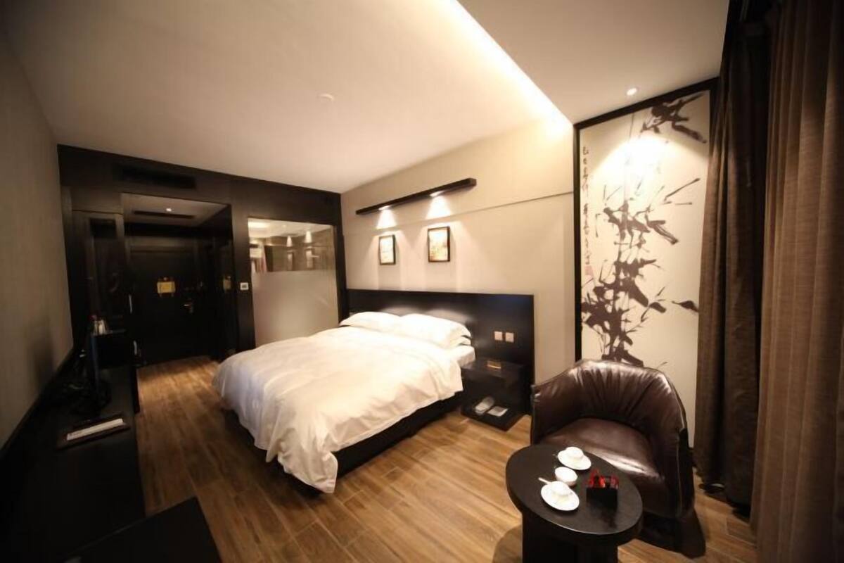 Una habitación de hotel moderna con una cama grande, una zona de estar con una mesa y una obra de arte colgada en la pared.