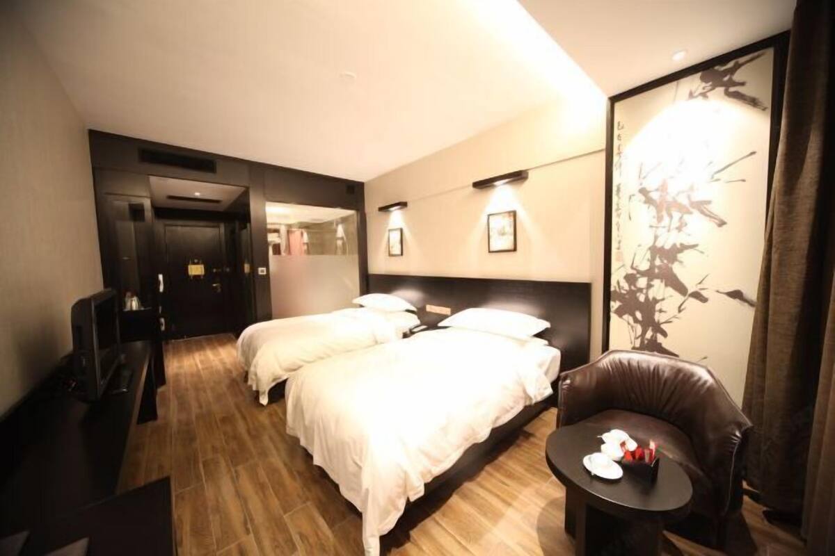 Una habitación de hotel con una cama, un escritorio, una silla y una mesita con velas.
