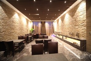 Un vestíbulo de hotel con paredes de piedra, suelo de mármol y una recepción.