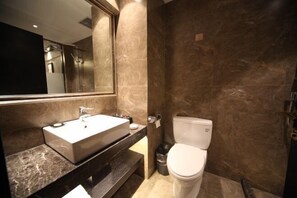 Een moderne badkamer met een marmeren wastafel, toilet en een grote spiegel.