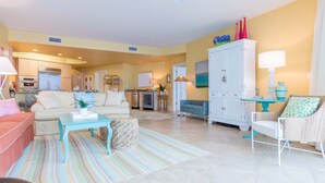 A spacious living area with a sofa, armchair, and coffee table. There is a kitchen in the background with a refrigerator and cabinets. - Cozy Three Bedroom Bayside Unit with Gorgeous Bay Views! Complimentary Boat Slip! (Orange Beach)