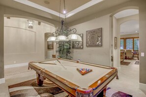 A pool table in a room with a chandelier, a potted plant, and artwork on the walls. - Palm Oasis: Pool, Spa, Putting Green, BBQ! (Indio)