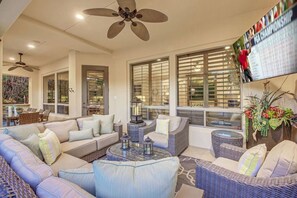 A spacious living area with a sofa set, a coffee table, and a television mounted on the wall.