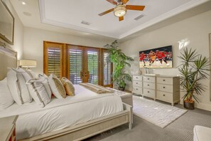 A bedroom with a bed, a dresser, a ceiling fan, and a large window with blinds.