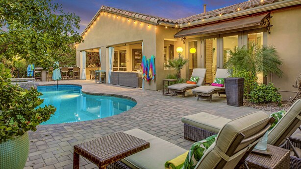 A poolside area with lounge chairs, a small table, and a covered patio. - Palm Oasis: Pool, Spa, Putting Green, BBQ! (Indio)