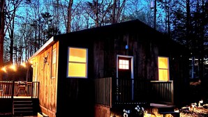 Une cabane en bois avec une véranda, deux fenêtres et une porte.