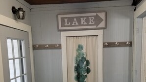 A room with a door labeled 'LAKE', a window, a wall-mounted light fixture, and a patterned rug. - That Cottage by the Lake!! (Canandaigua)