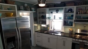 A modern kitchen with stainless steel appliances, white cabinets, and a black countertop. - That Cottage by the Lake!! (Canandaigua)