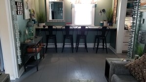 A compact kitchen with a dining area, featuring a central island, chairs, and a ceiling fan. - That Cottage by the Lake!! (Canandaigua)