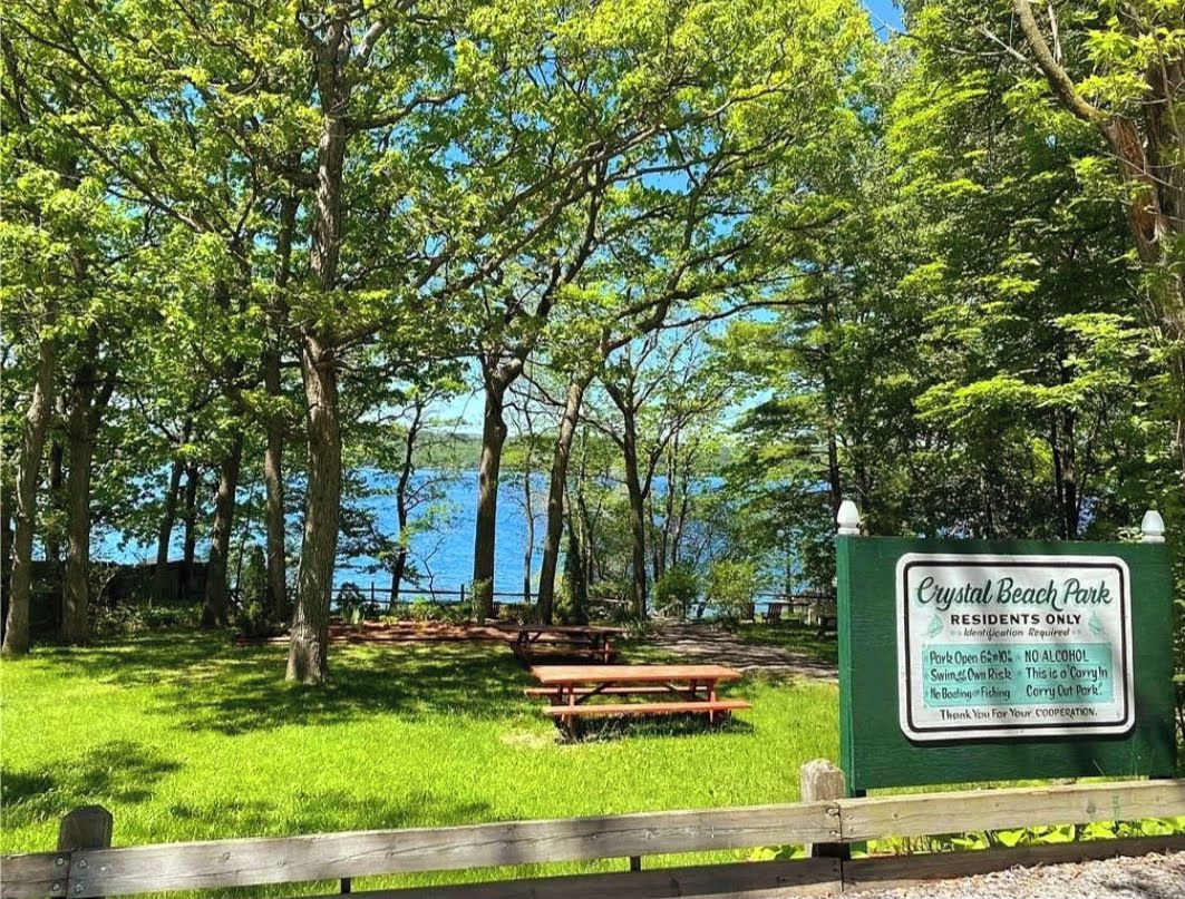 Parque Crystal Beach con mesas de picnic y un cartel que indica que es zona exclusiva para residentes, con normas espec íficas.
