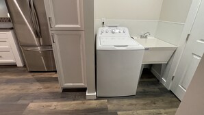 A compact kitchen with a stainless steel refrigerator, a built-in oven, and a washing machine. - NEW, Super Comfortable Ranch! (Mentor)