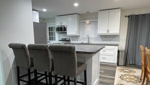 A modern kitchen with a central island, bar stools, and a stainless steel refrigerator. - NEW, Super Comfortable Ranch! (Mentor)