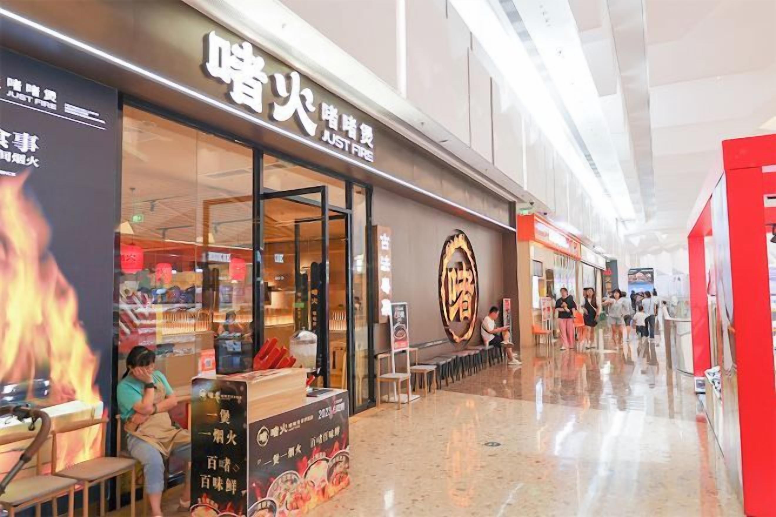 A shopping mall corridor with a restaurant on the left and a red structure on the right.