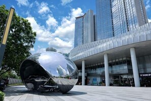 Un bâtiment moderne avec une grande sculpture réfléchissante devant l’entrée.
