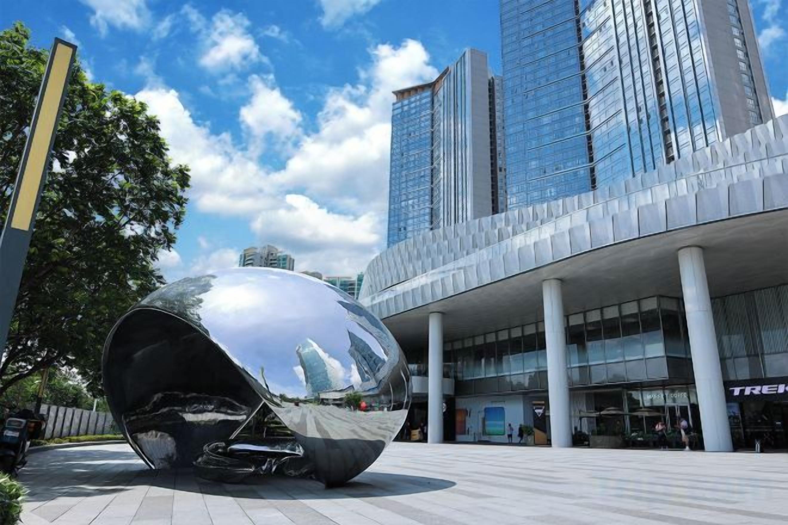 A modern building with a spherical sculpture in front.