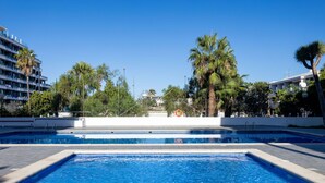 Une piscine à l’eau d’un bleu cristallin, entourée de palmiers et avec un bâtiment blanc en arrière-plan.