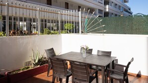 Une terrasse sur le toit, avec une table et des chaises, entourée de plantes en pot.