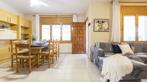 A spacious living area with a dining table and chairs, a sofa, and a large window with curtains. - Stunning private villa for 9 guests with WIFI, A/C, private pool, TV, patio and pets allowed (Deltebre)