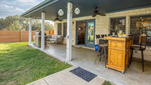 A covered patio with a bar area, outdoor seating, and a grill. - Stylish Ranch House | Renovated Interior + Backyard Pool Oasis (Dripping Springs)