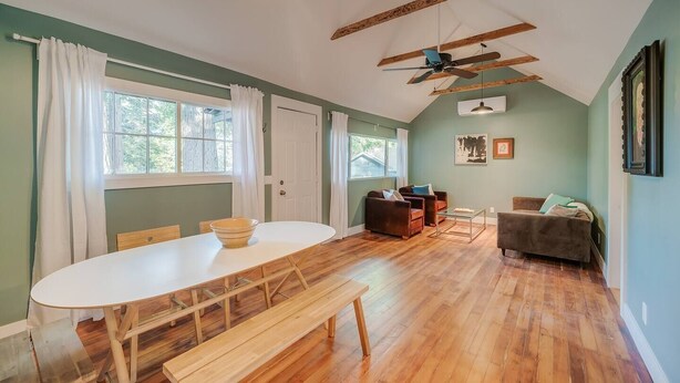 A spacious room with a wooden dining table, benches, a sofa, and a ceiling fan.