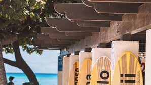 Eine Reihe von Surfbrettern mit dem Schriftzug 'Hawaii', unter einer Konstruktion mit Blick auf den Ozean platziert.