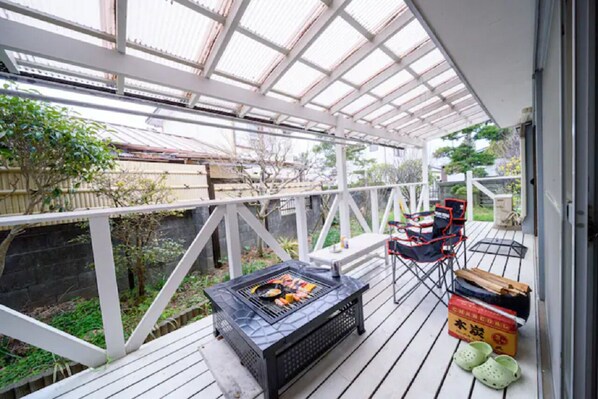 A covered outdoor area with a grill, seating, and storage boxes. - Bettei Tateyama (Tateyama)