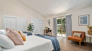 Camera da letto con un letto grande, una scrivania, un divano e una porta scorrevole in vetro che dà su un balcone.