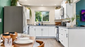 Una cucina moderna con mobili bianchi, un piano di lavoro in granito e una finestra che lascia entrare luce naturale.