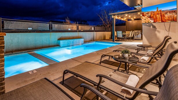 Un área de piscina al aire libre con sillones de descanso y una zona de barbacoa.