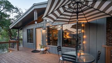 A wooden deck with a table and chairs, an umbrella, and string lights.