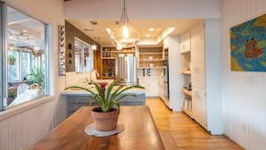 Een moderne keuken met houten vloeren, een centraal kookeiland en een potplant.