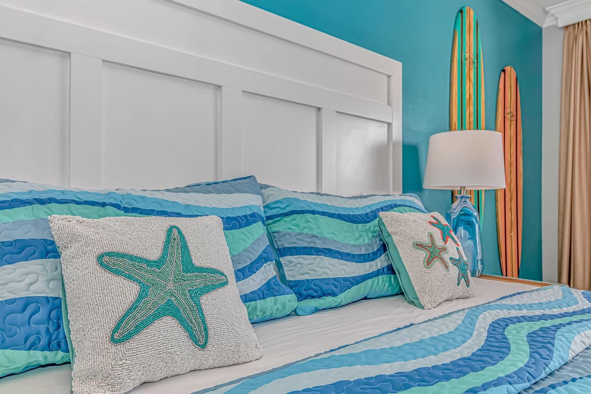 A bed with blue and white bedding, starfish pillows, and a striped wall.