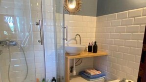 Un bagno moderno con doccia in vetro, lavandino, bidet e un piccolo tappeto decorativo a forma di ananas.