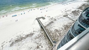 Ein Strand mit Sonnenschirmen und einem Steg, der ins Wasser führt.