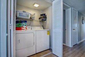 A laundry area with a washing machine, dryer, and stacked laundry. - Top Floor Oceanfront & Sound Views, Pool, (North Topsail Beach)