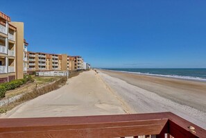 Un hotel frente a la playa con varios balcones, una playa de arena y una vista despejada del océano.