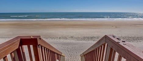 Una escalera de madera que conduce a una playa con vistas claras al océano.