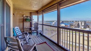 A covered outdoor area with a view of a beach and buildings. - Top Floor Oceanfront & Sound Views, Pool, (North Topsail Beach)