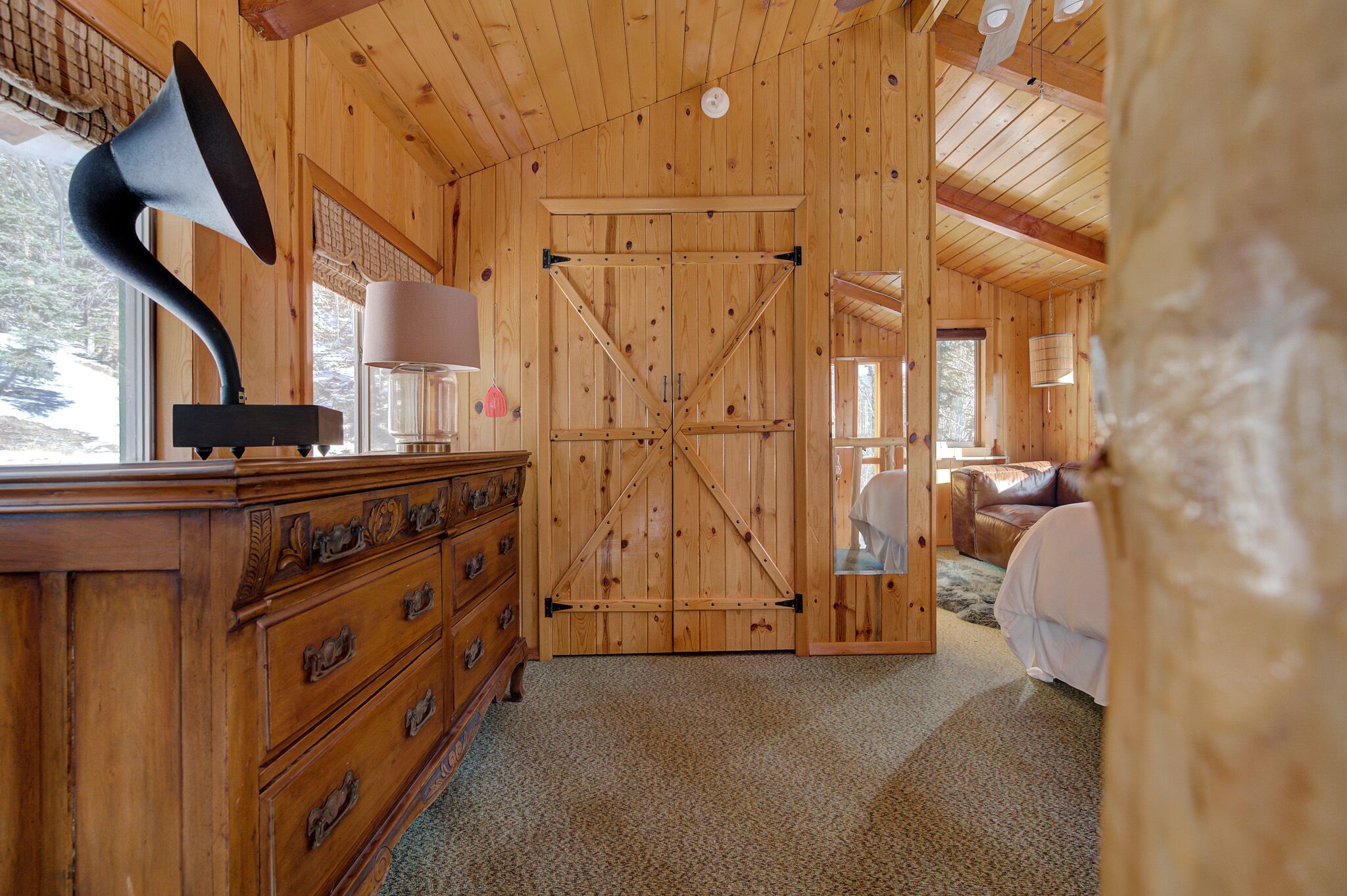 Un interior de madera con una puerta grande de madera, un aparador con varios cajones y una lámpara.