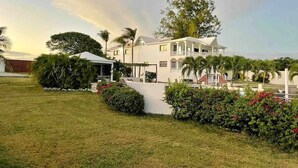 A large, two-story house with a covered patio and a well-maintained lawn.