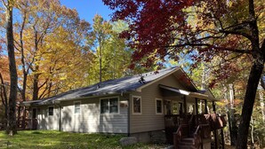 Une cabane dotée d’une véranda, d’un chemin en pierre et bordée par une forêt.