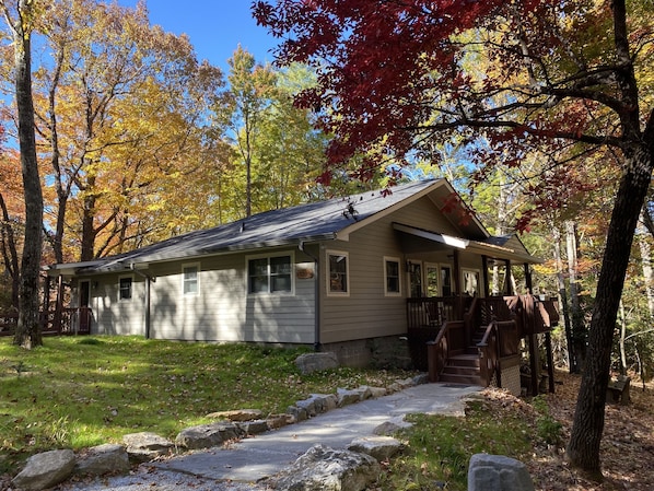 A cabin with a porch, a stone pathway, and a forested backdrop.