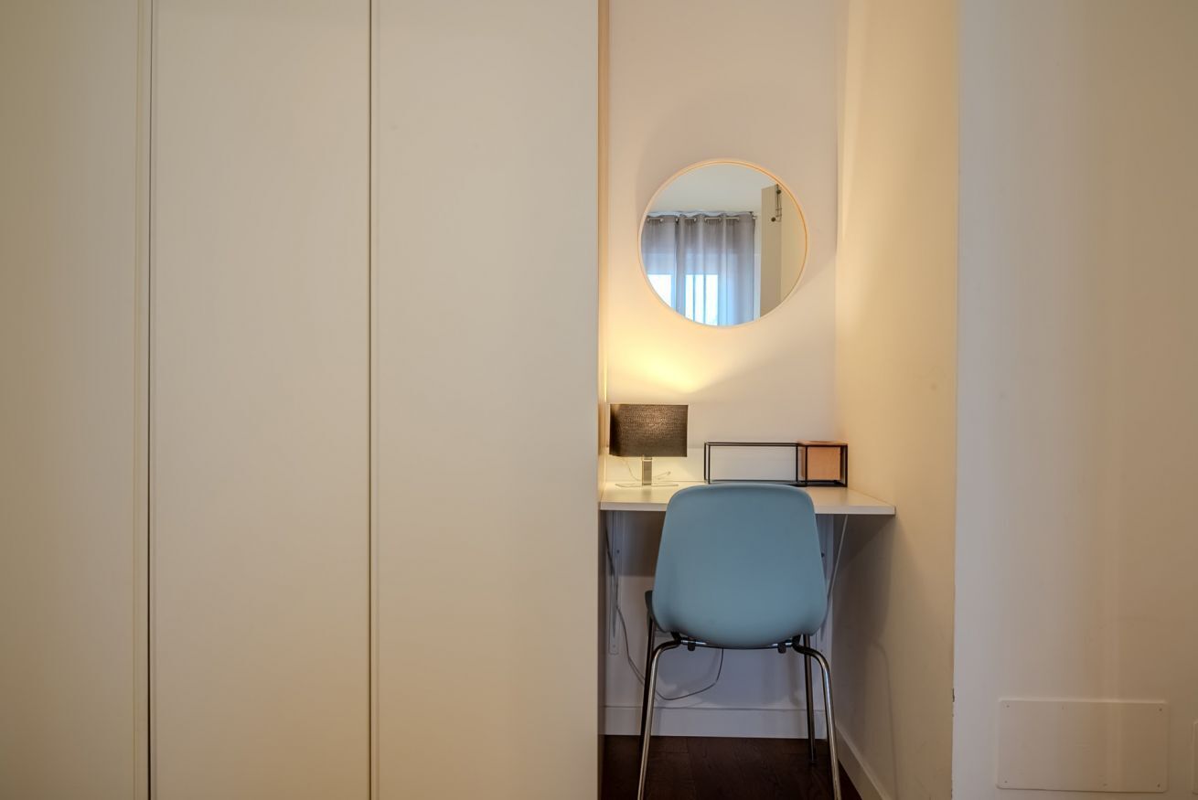 Una oficina pequeña y privada con un escritorio, una silla y un espejo redondo en la pared.