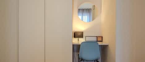 Una oficina pequeña y privada con un escritorio, una silla y un espejo redondo en la pared.